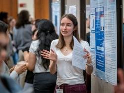一个学生在讨论她的研究海报时做手势.